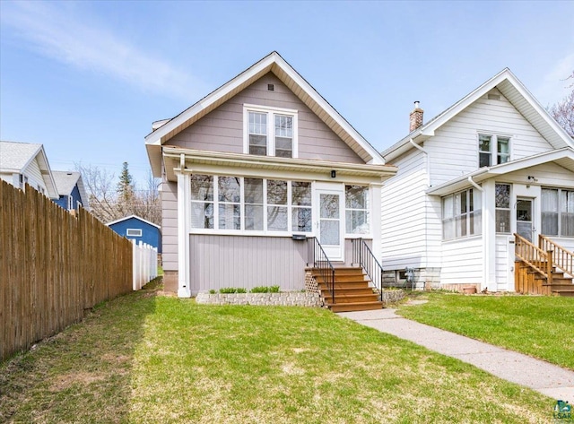 bungalow featuring a sunroom, a front yard, fence, and entry steps