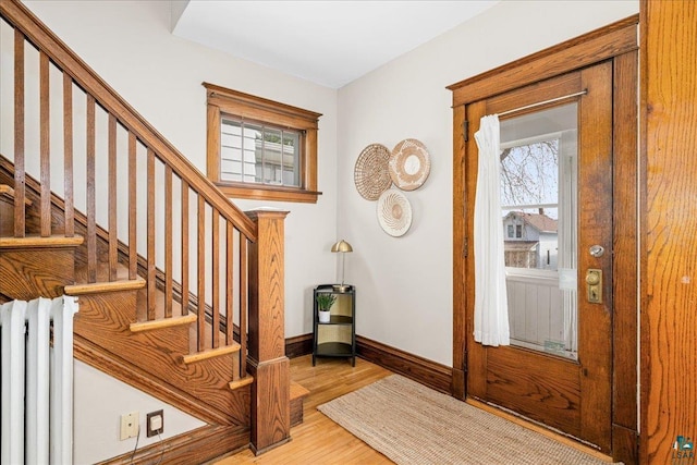 foyer with baseboards, stairs, wood finished floors, and radiator