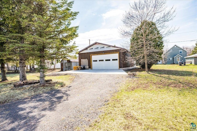 view of front of house featuring a detached garage, an outdoor structure, a front yard, and gravel driveway