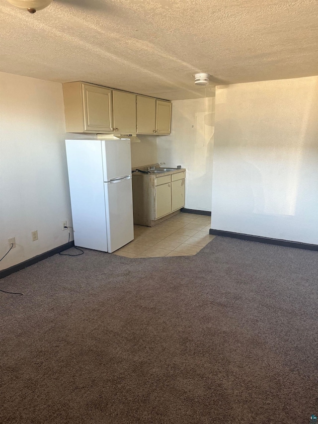 kitchen featuring baseboards, freestanding refrigerator, a textured ceiling, and light carpet