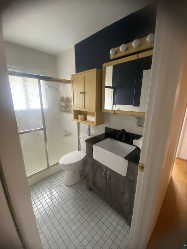 bathroom with a shower stall, backsplash, tile patterned flooring, and toilet