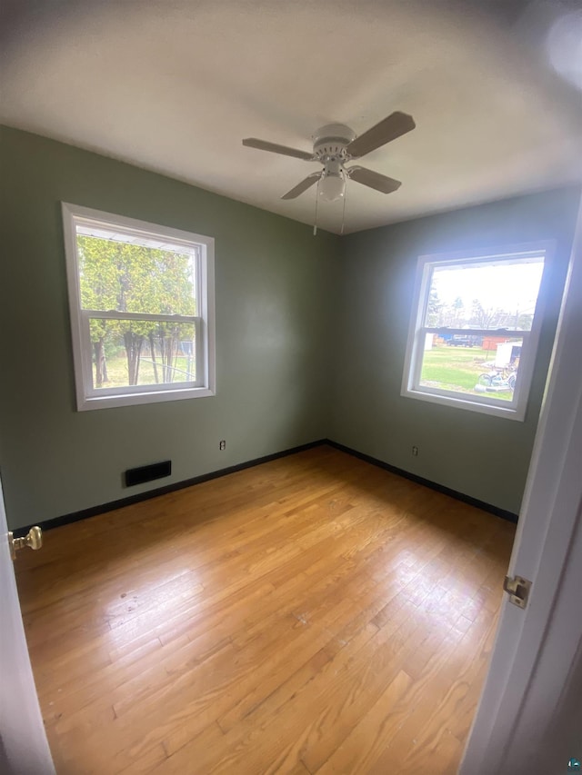 unfurnished room with ceiling fan, light wood-style flooring, visible vents, and plenty of natural light
