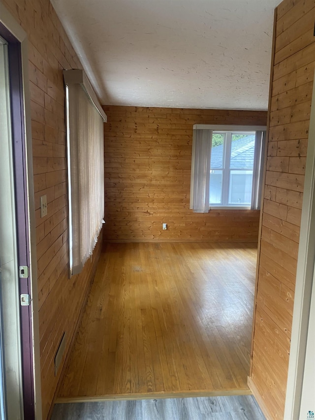spare room with wood walls and hardwood / wood-style floors