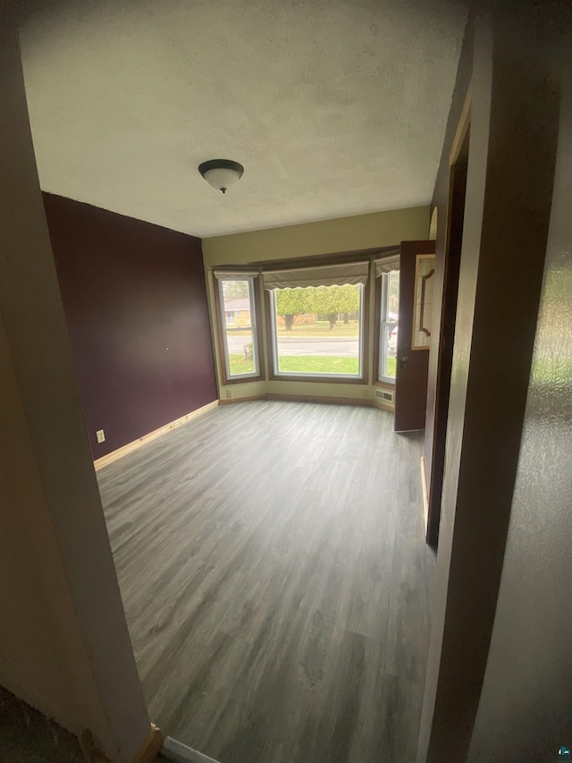 unfurnished room featuring baseboards, visible vents, and wood finished floors