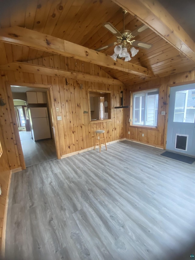 unfurnished living room with wood ceiling, wood finished floors, a ceiling fan, vaulted ceiling with beams, and wood walls