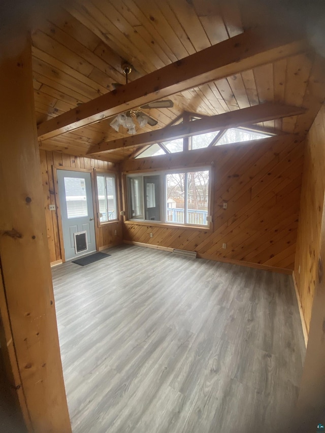 unfurnished living room with wood walls, wooden ceiling, vaulted ceiling with beams, and wood finished floors