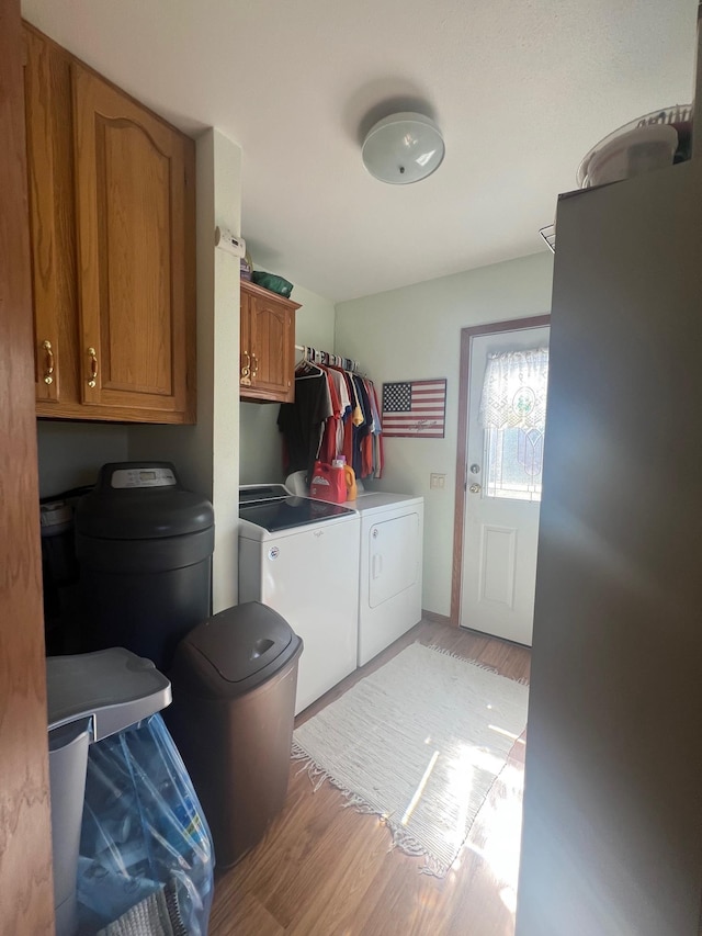 laundry room featuring cabinet space, light wood-type flooring, and washer and dryer