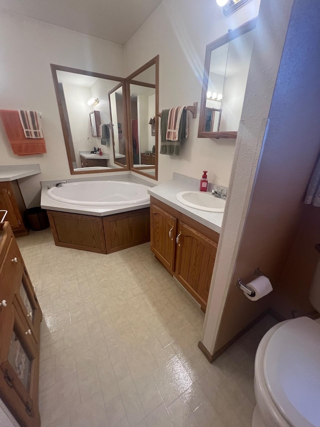 full bathroom featuring vanity, toilet, a garden tub, and tile patterned floors