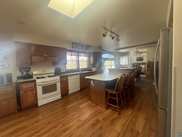 kitchen with stainless steel appliances, a kitchen island, a ceiling fan, and wood finished floors