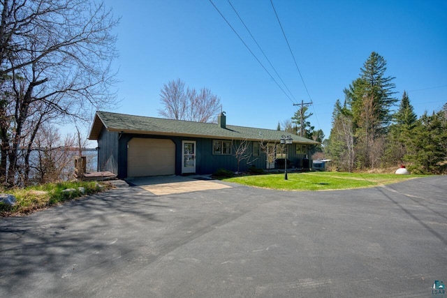 46040 State Highway 65, Nashwauk, MN 55769 - ranch-style home with aphalt driveway, a garage, a front lawn, a chimney, and board and batten siding