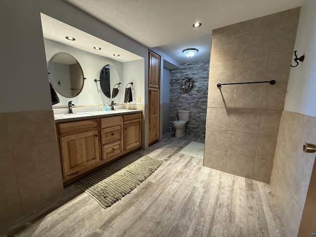 46040 State Highway 65, Nashwauk, MN 55769 - full bath featuring tile walls, toilet, a sink, tiled shower, and wood finished floors