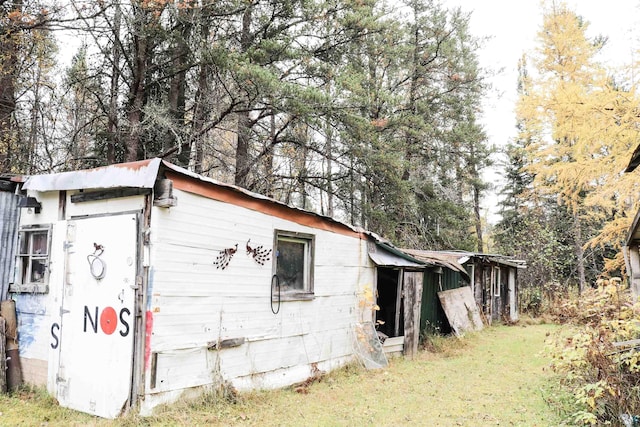 view of property exterior with a lawn and an outbuilding