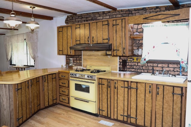 kitchen with a peninsula, white range with gas stovetop, a sink, light wood-type flooring, and beamed ceiling