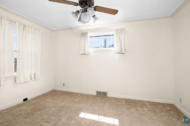unfurnished room with ceiling fan, carpet floors, baseboards, and visible vents