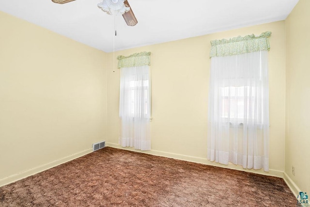 spare room with carpet, visible vents, baseboards, and ceiling fan