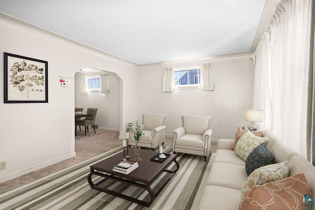 living room with arched walkways, baseboards, and carpet floors