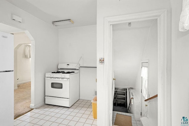 kitchen featuring white appliances, arched walkways, and light tile patterned floors