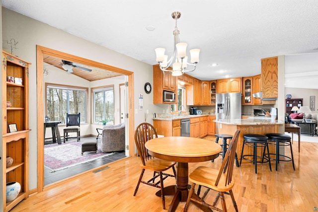 dining room with light wood-style flooring, ceiling fan with notable chandelier, visible vents, lofted ceiling, and recessed lighting