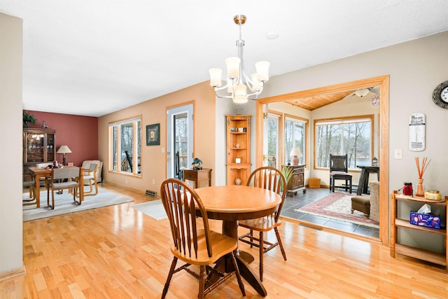 dining space with a chandelier, lofted ceiling, baseboards, and light wood-type flooring
