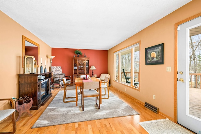 dining space featuring a fireplace, visible vents, and wood finished floors