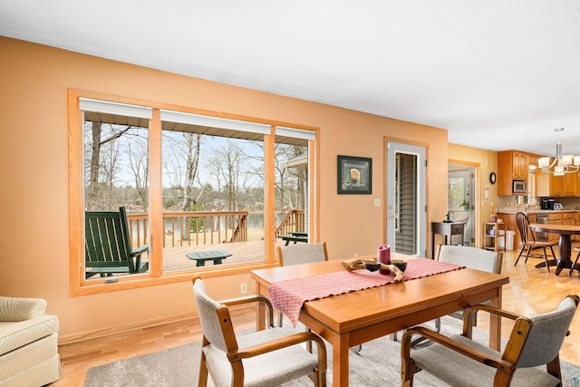 dining area with light wood finished floors, baseboards, and a notable chandelier