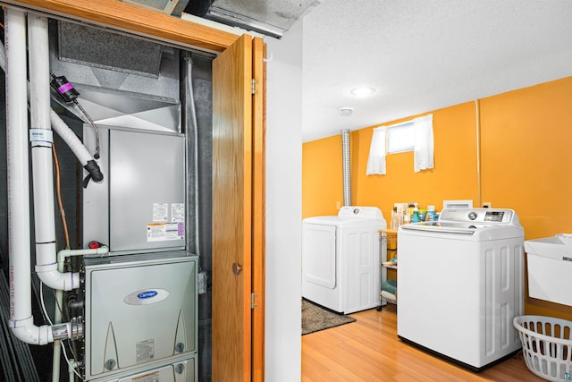 washroom with heating unit, wood finished floors, a sink, separate washer and dryer, and laundry area