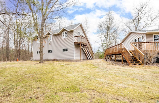 rear view of house with a yard, stairs, and a wooden deck