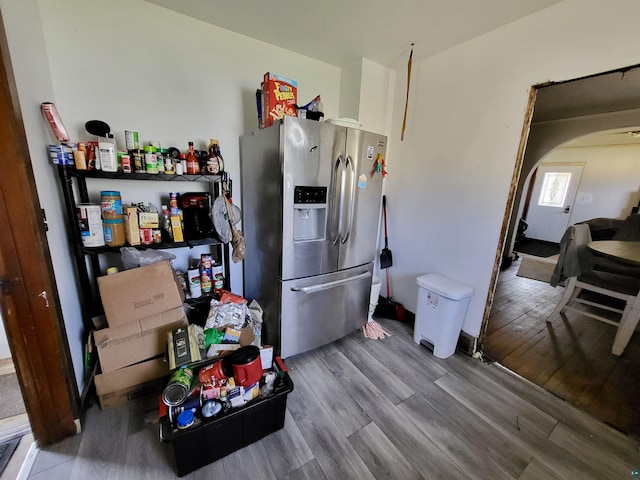 kitchen featuring stainless steel fridge, wood finished floors, and arched walkways