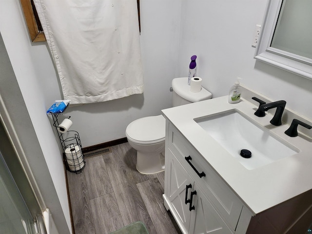 bathroom featuring toilet, wood finished floors, vanity, visible vents, and baseboards