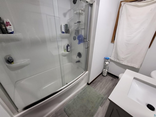 bathroom with a sink, toilet, shower / bath combination with glass door, and wood finished floors