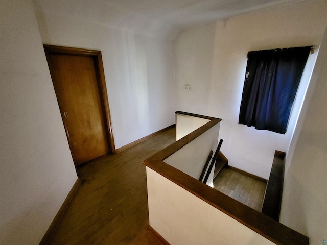 hallway with baseboards, an upstairs landing, and vaulted ceiling