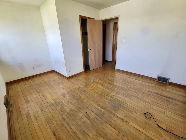 empty room featuring visible vents, baseboards, and hardwood / wood-style flooring