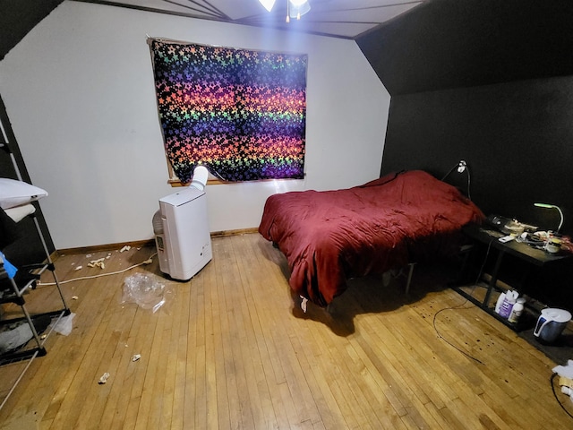 bedroom with vaulted ceiling, baseboards, and hardwood / wood-style flooring