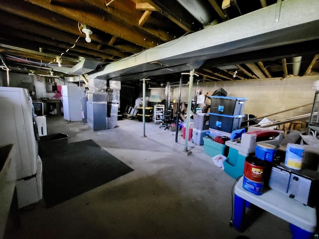 unfinished basement with freestanding refrigerator and heating unit