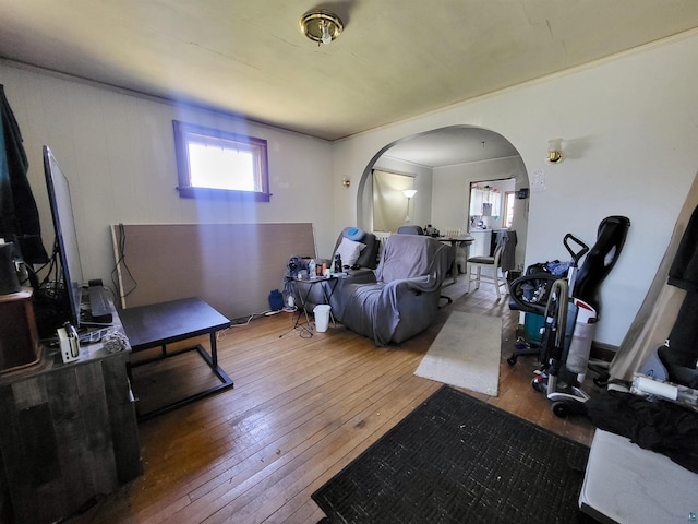 living room with arched walkways and hardwood / wood-style flooring