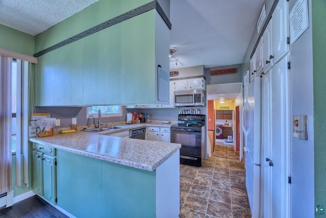 kitchen with a peninsula, a sink, black range with electric cooktop, stainless steel microwave, and light countertops