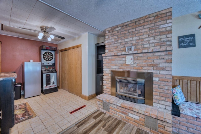 kitchen featuring freestanding refrigerator, a brick fireplace, ceiling fan, and wood finished floors