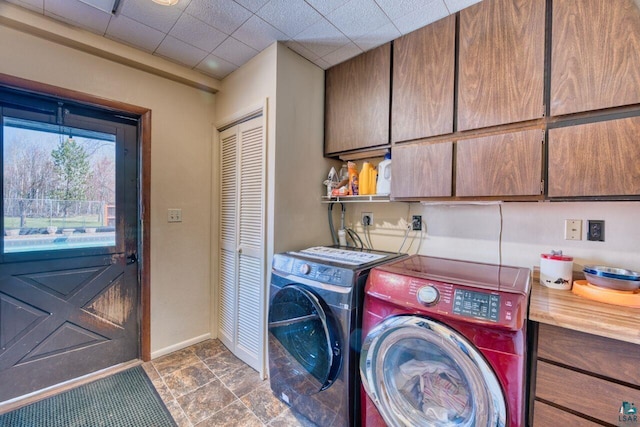 laundry room with washing machine and dryer, cabinet space, and baseboards
