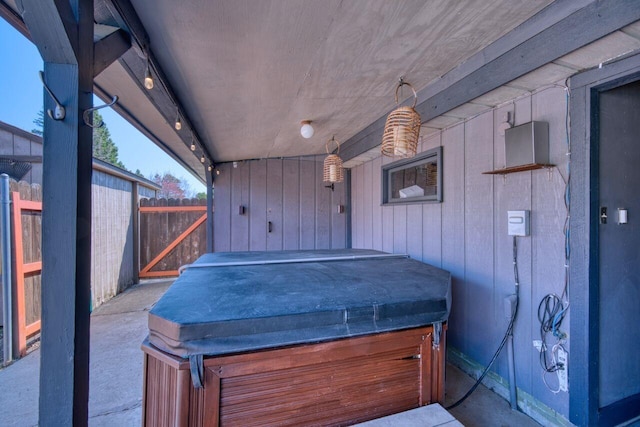 view of patio with a hot tub and fence