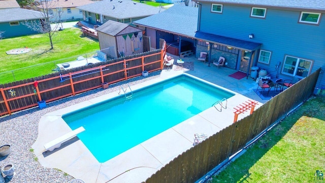 view of pool featuring a patio, a diving board, a lawn, a fenced backyard, and a fenced in pool