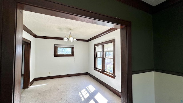 spare room with light carpet, ornamental molding, a chandelier, and baseboards