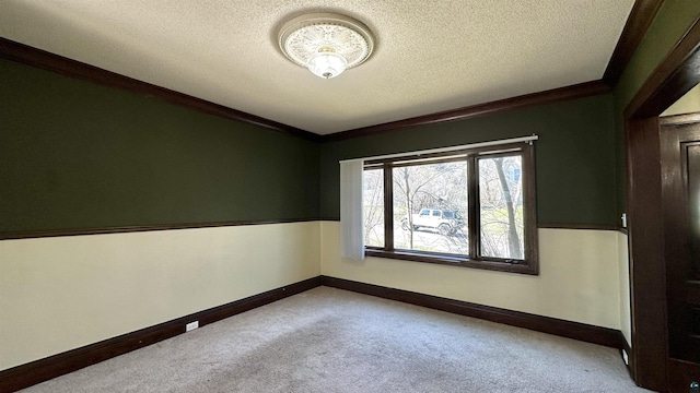 carpeted spare room featuring a textured ceiling, ornamental molding, and baseboards