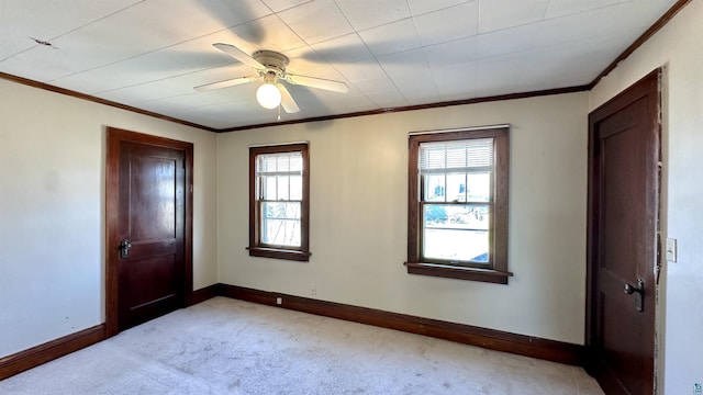 carpeted foyer featuring baseboards, healthy amount of natural light, crown molding, and a ceiling fan