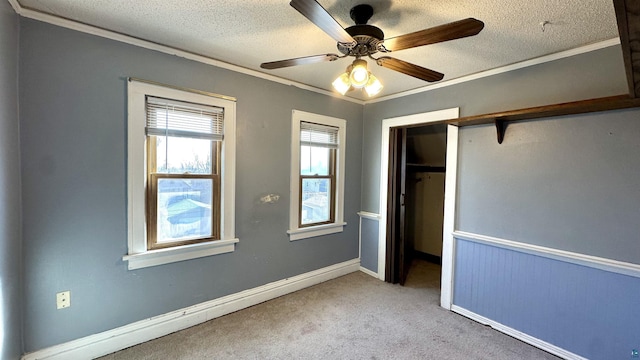 unfurnished bedroom with ornamental molding, a textured ceiling, carpet, a closet, and ceiling fan
