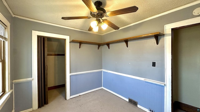 unfurnished bedroom featuring a textured ceiling, carpet flooring, crown molding, baseboards, and a ceiling fan