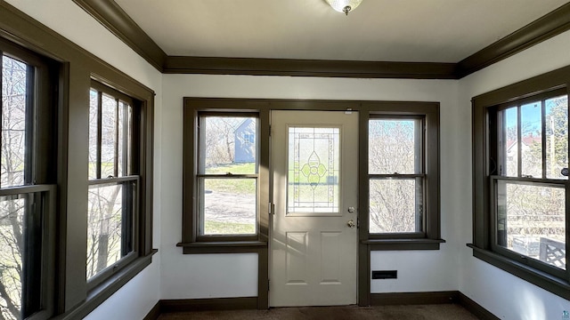 doorway to outside with baseboards, dark carpet, and crown molding