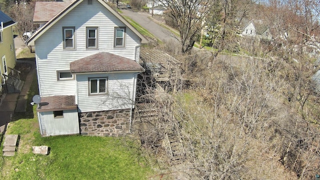 rear view of property with roof with shingles and a lawn