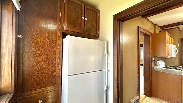 kitchen featuring white appliances and brown cabinetry