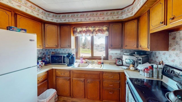 15 W 8th Ave, Grand Marais, MN 55604 - kitchen featuring freestanding refrigerator, electric stove, a sink, brown cabinets, and wallpapered walls