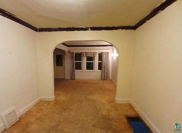 hall with arched walkways, ornamental molding, carpet, and baseboards